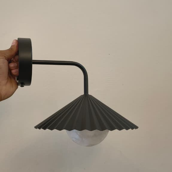 Wall-mounted light fixture with pleated design on a plain background