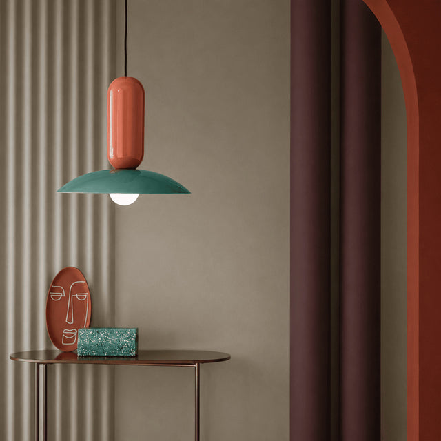 Colorful pendant lamp hanging above a small table with decorative items against a neutral wall.