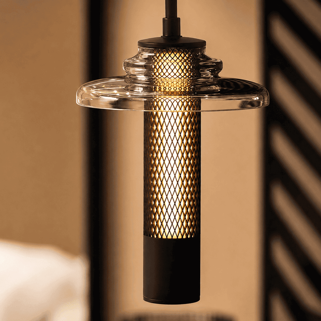 Modern pendant light with clear glass shade and black metal fixture against a blurred background