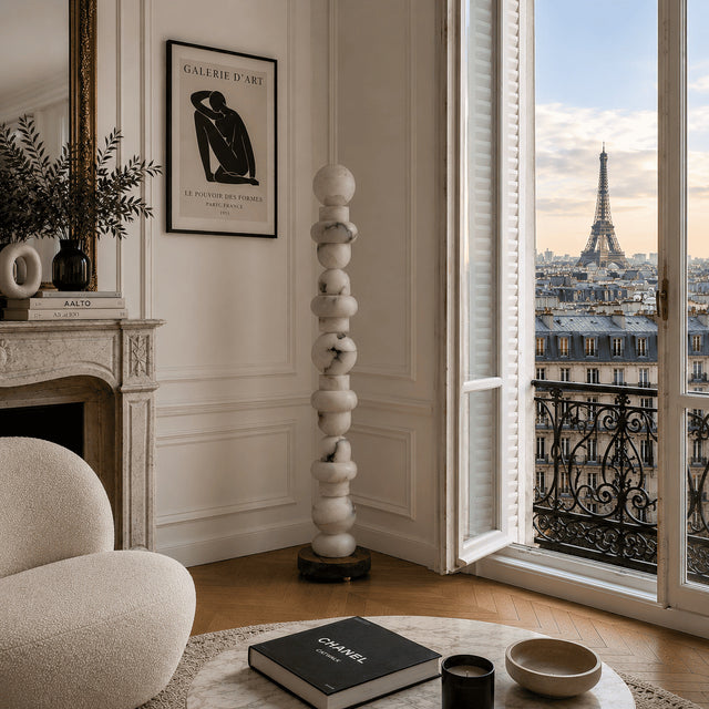 Living room with a view of the Eiffel Tower, featuring a fireplace, sculpture, and books.