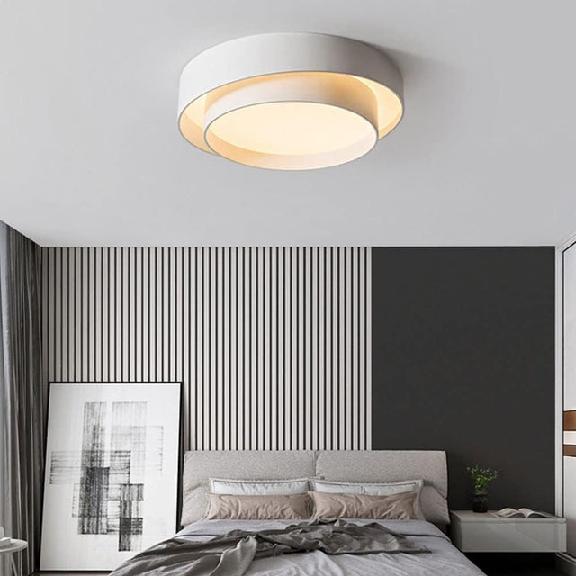 Modern bedroom with a ceiling light fixture, bed, and abstract wall art.