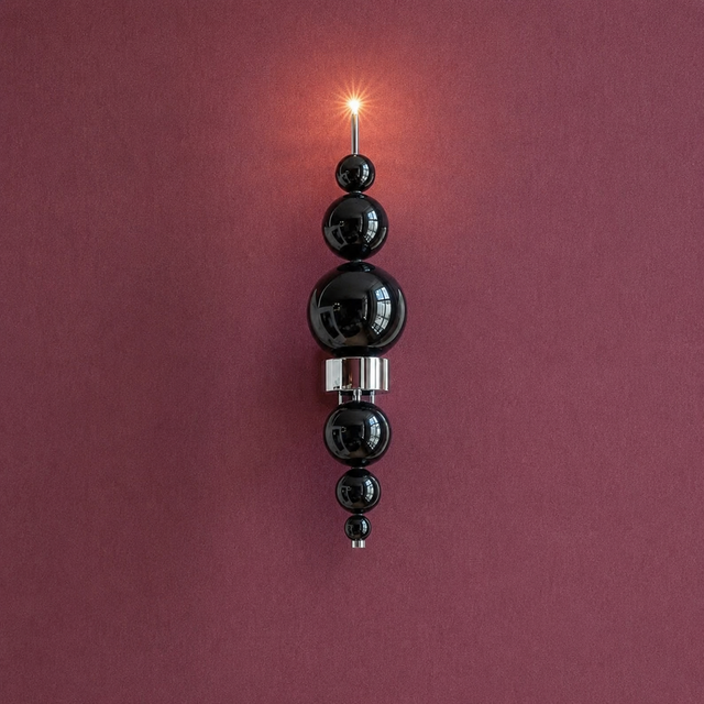 Decorative wall light fixture with black spherical elements on a maroon background