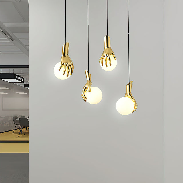 Gold hand-shaped pendant lights hanging against a gray wall.