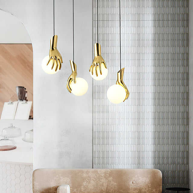Gold hand-shaped pendant lights hanging in a modern interior setting.