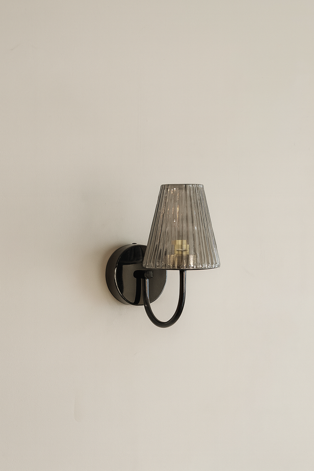 Wall-mounted lamp with a textured shade on a plain wall