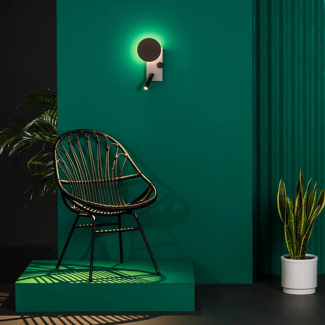 Wicker chair against a green wall with a neon light fixture.