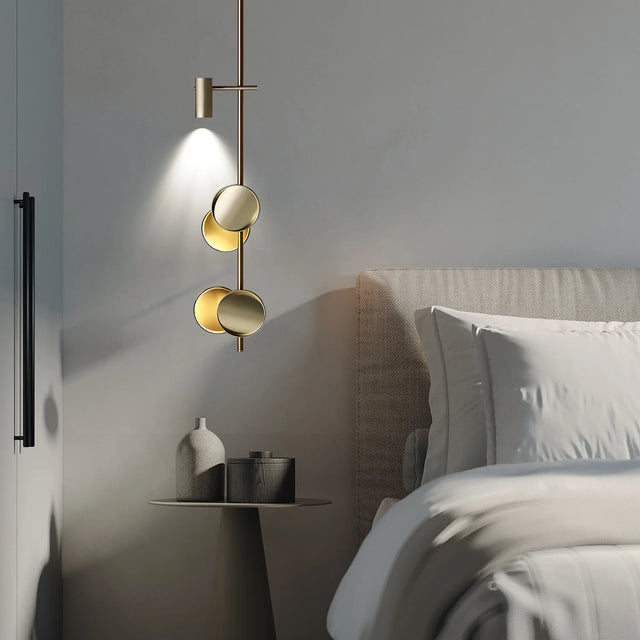 Modern pendant light fixture in a bedroom setting with a bed and nightstand.