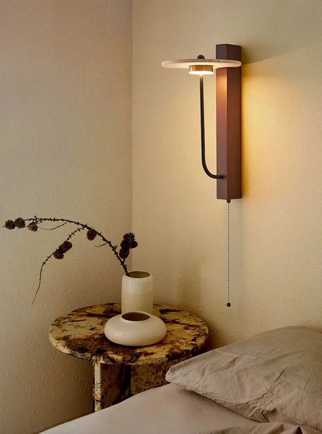 Wall-mounted light fixture in a bedroom setting with a side table and decorative elements.
