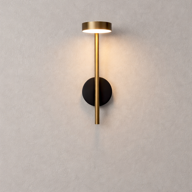 Modern wall lamp with gold and black design on a light gray wall