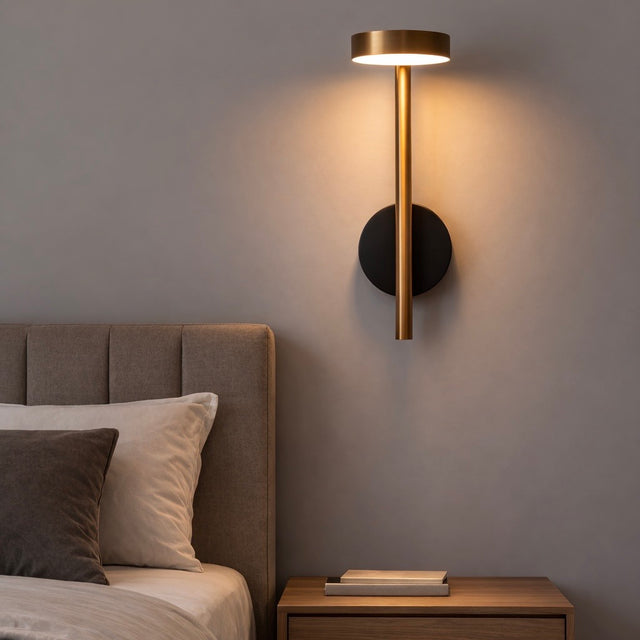 Modern wall sconce on a gray wall above a bed with a wooden nightstand.