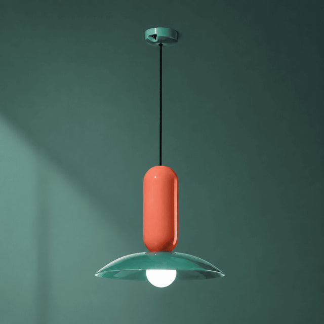 Pendant light with a coral shade and green base against a teal background