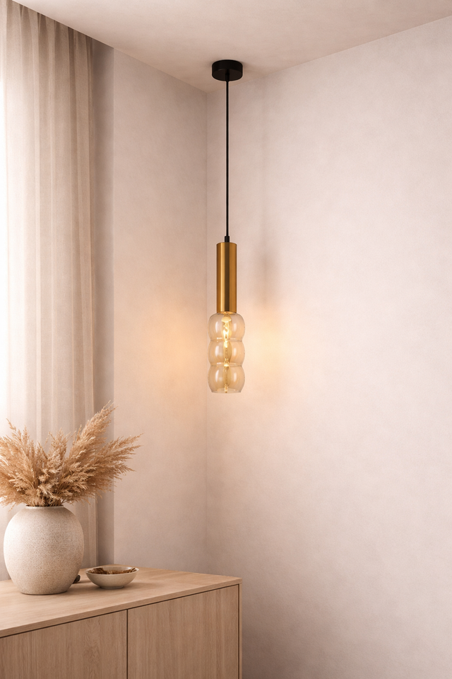 Modern pendant light with gold finish hanging in a room with neutral decor.