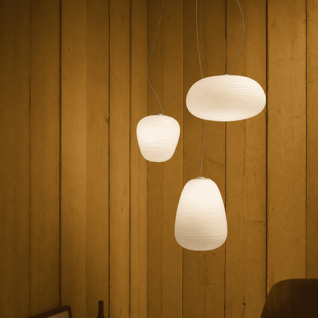 Three white pendant lights hanging against a wooden panel wall.