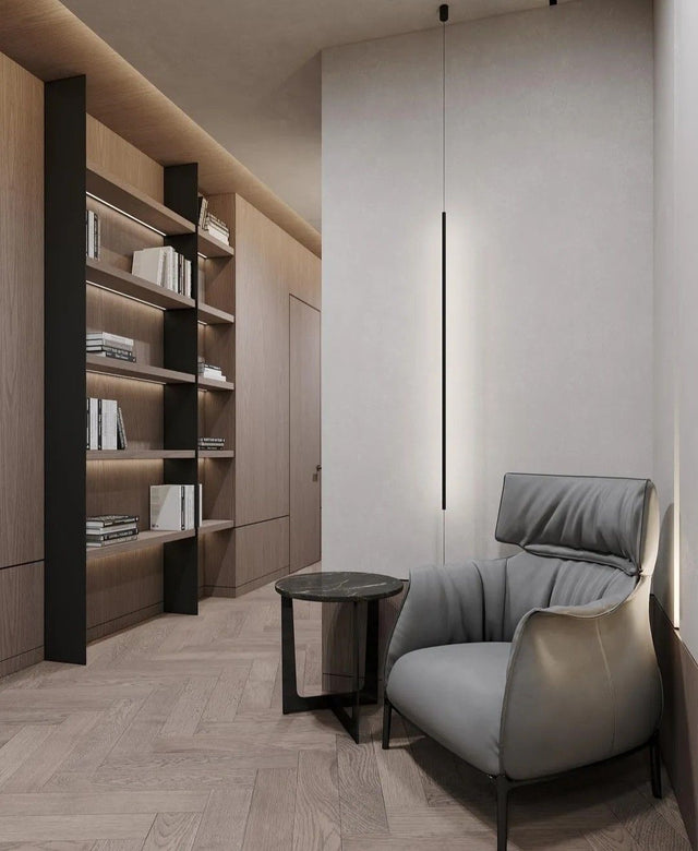 Modern interior with a gray armchair, small round table, and bookshelves.