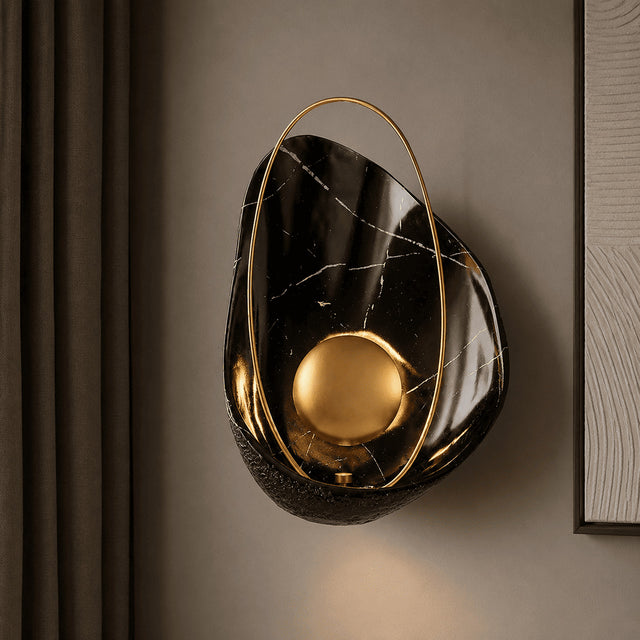 Decorative wall sconce with black marble and gold finish on a brown wall.