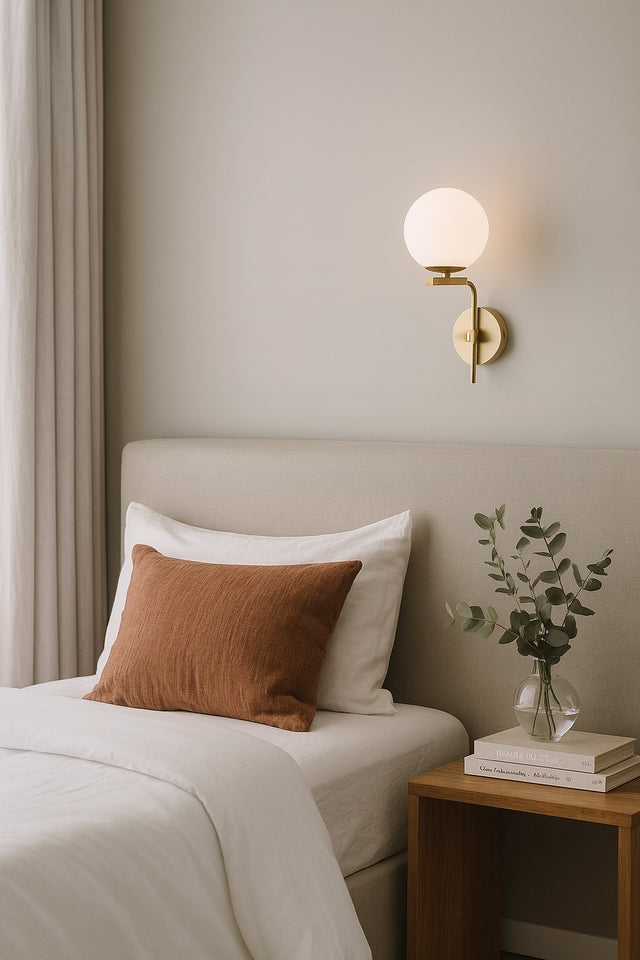 Neatly made bed with a nightstand and wall sconce in a bedroom setting