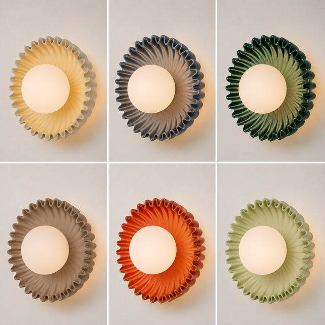 Six wall-mounted light fixtures arranged in a 2x3 grid, each with a scalloped circular shade and a glowing oval bulb. The shades come in warm yellow, dark gray, forest green, taupe, burnt orange, and sage green, all shown against a light neutral background.