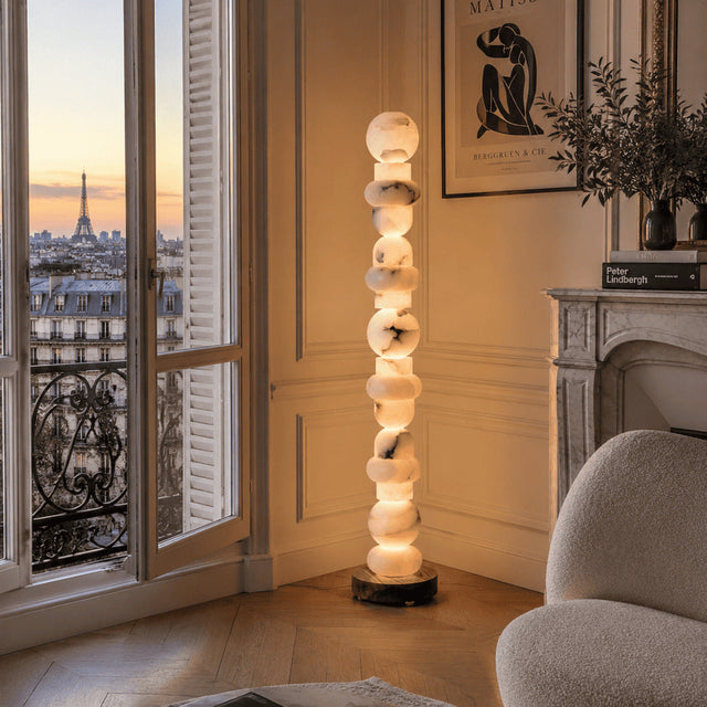 Modern interior with a tall floor lamp, Chanel book, and view of the Eiffel Tower.