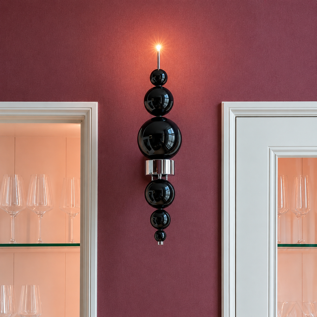 Wall-mounted decorative light fixture with black spherical elements on a pink wall.