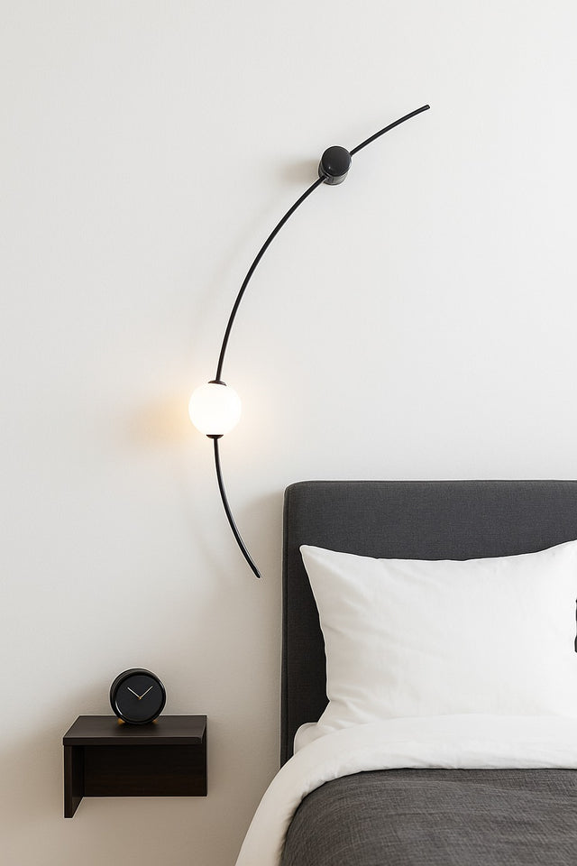 Modern bedroom with a bed, nightstand, and wall lamp.