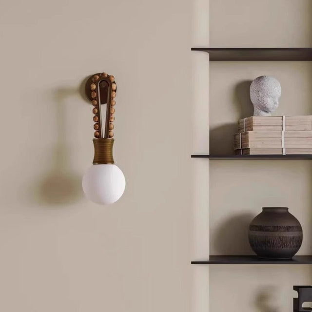 Decorative wall sconce with a white bulb on a beige wall with shelves and decor.