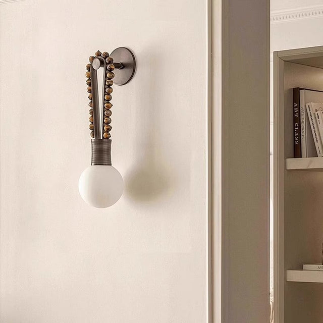 Wall-mounted light fixture with decorative design on a neutral wall.