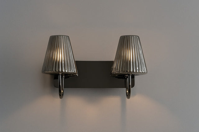 Wall-mounted light fixture with two ribbed lampshades on a plain wall.
