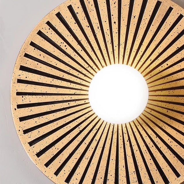 Round  light fixture with sunburst design on a gray background