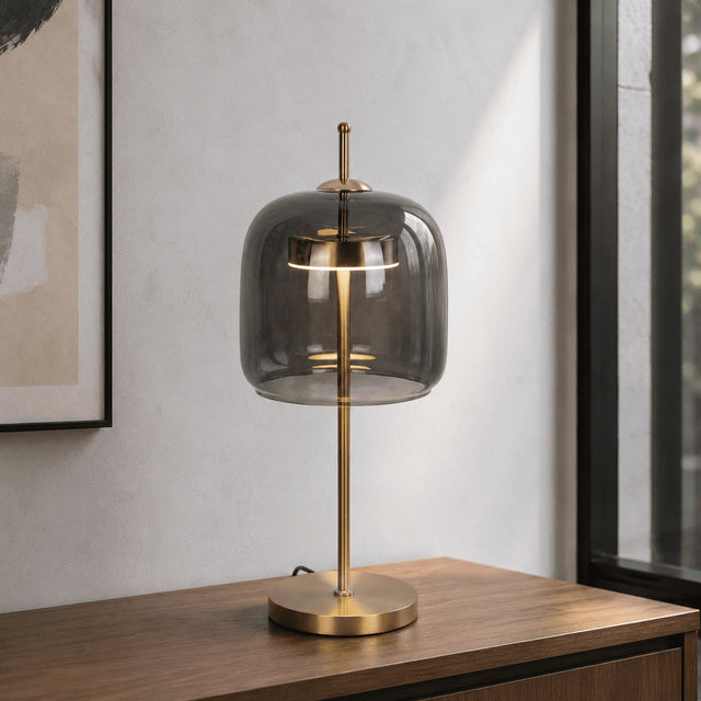 Table lamp with smoked glass shade and gold base on a wooden surface.