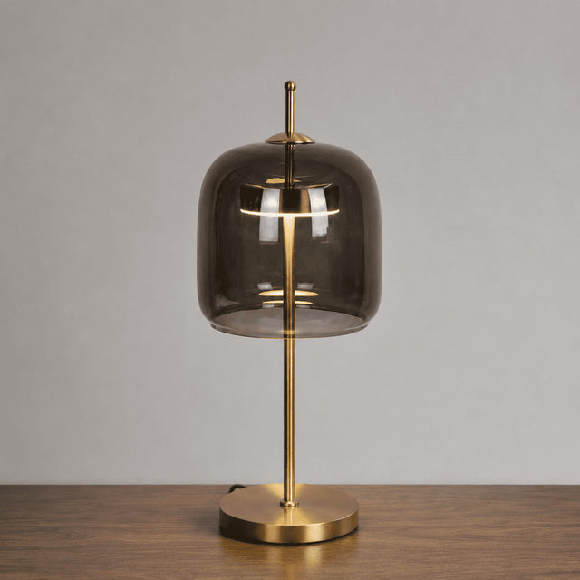 Table lamp with smoked glass shade and gold base on a wooden surface.